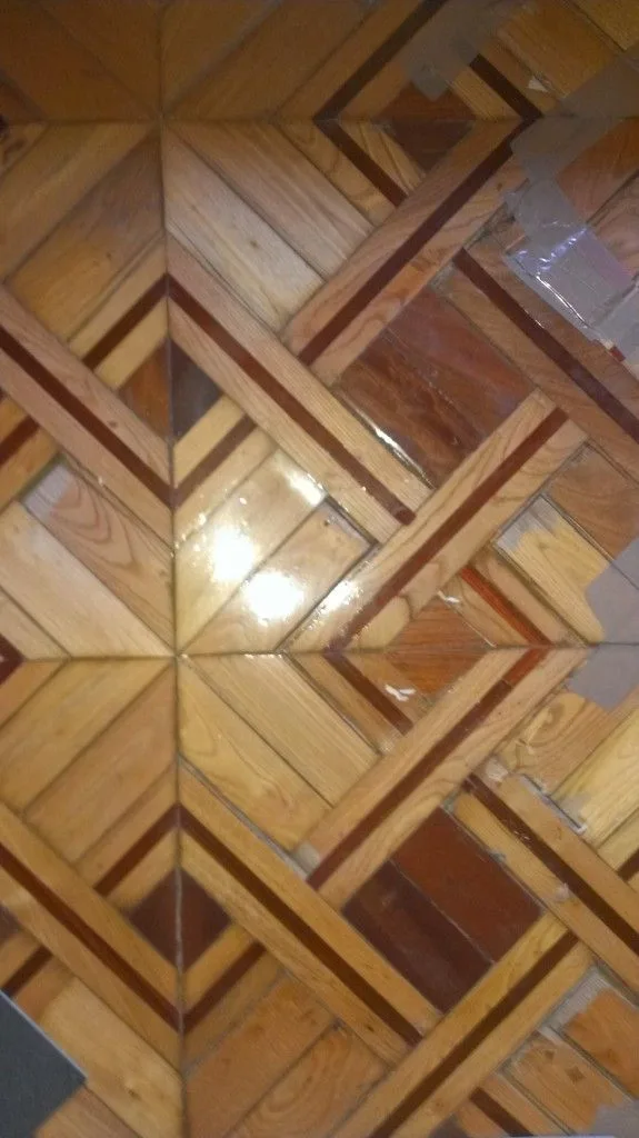 Baldosa de marqueteria pegada provisionalmente con cinta de embalar