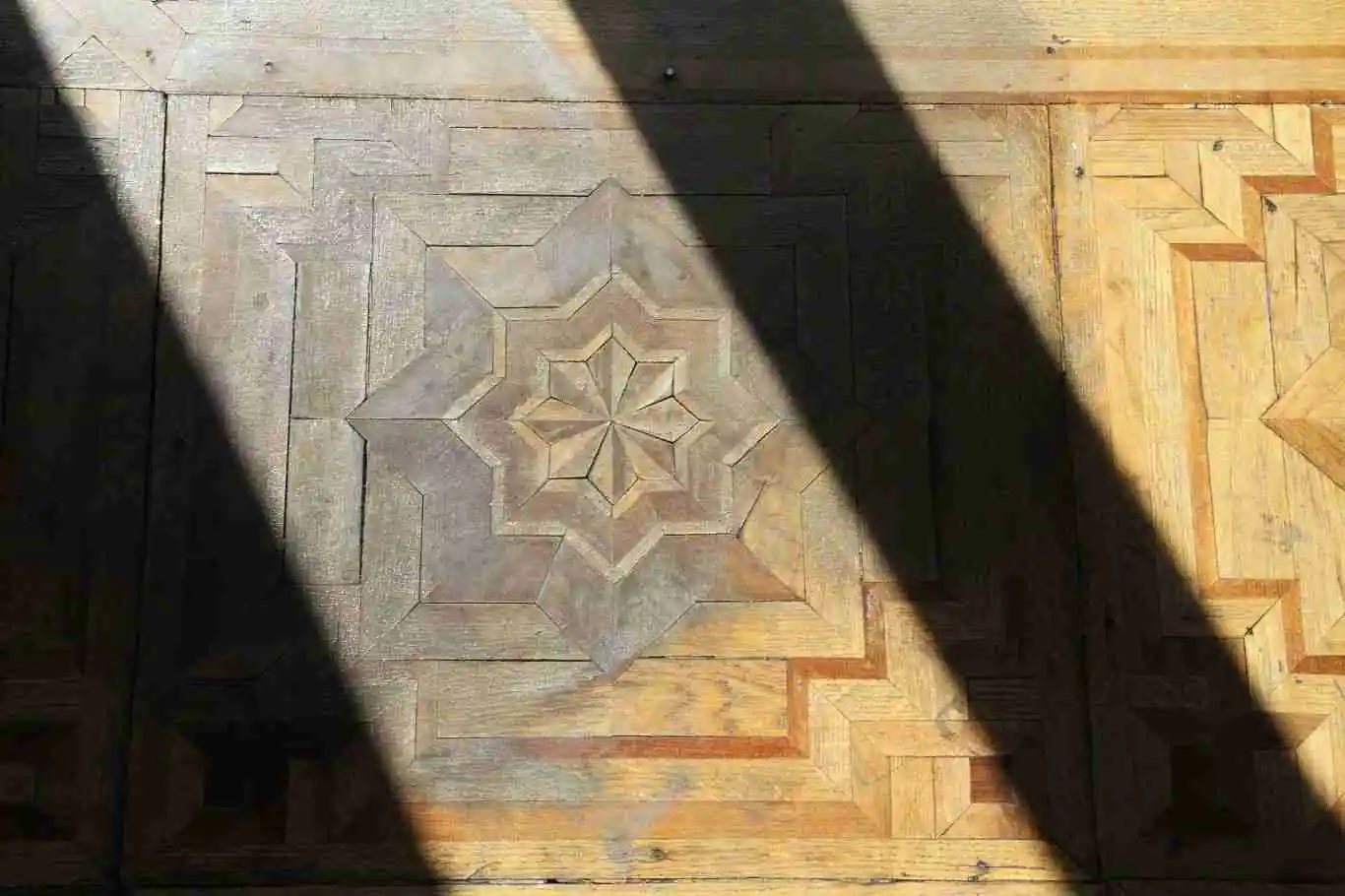 Parquet de marqueteria deteriorado con manchas, sombras y perdida de acabado