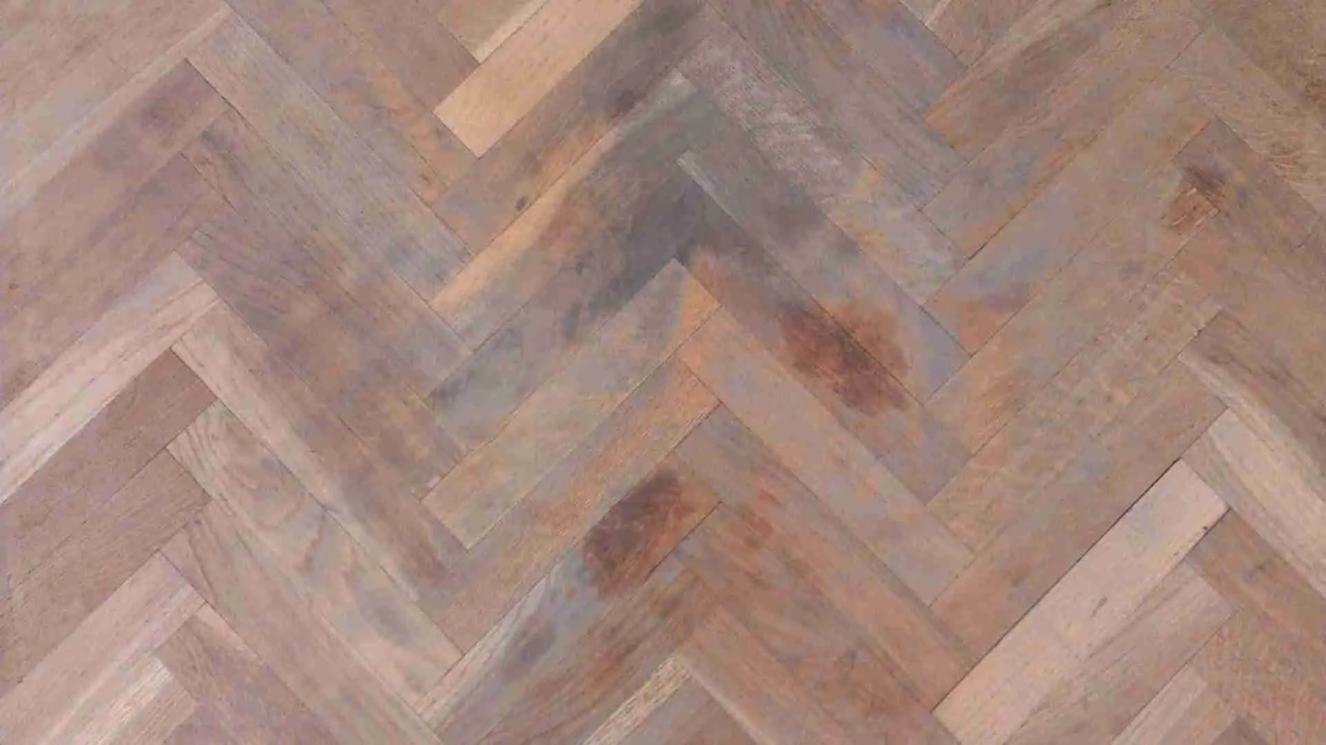 Parquet de roble en espiga con manchas oscuras de grasa