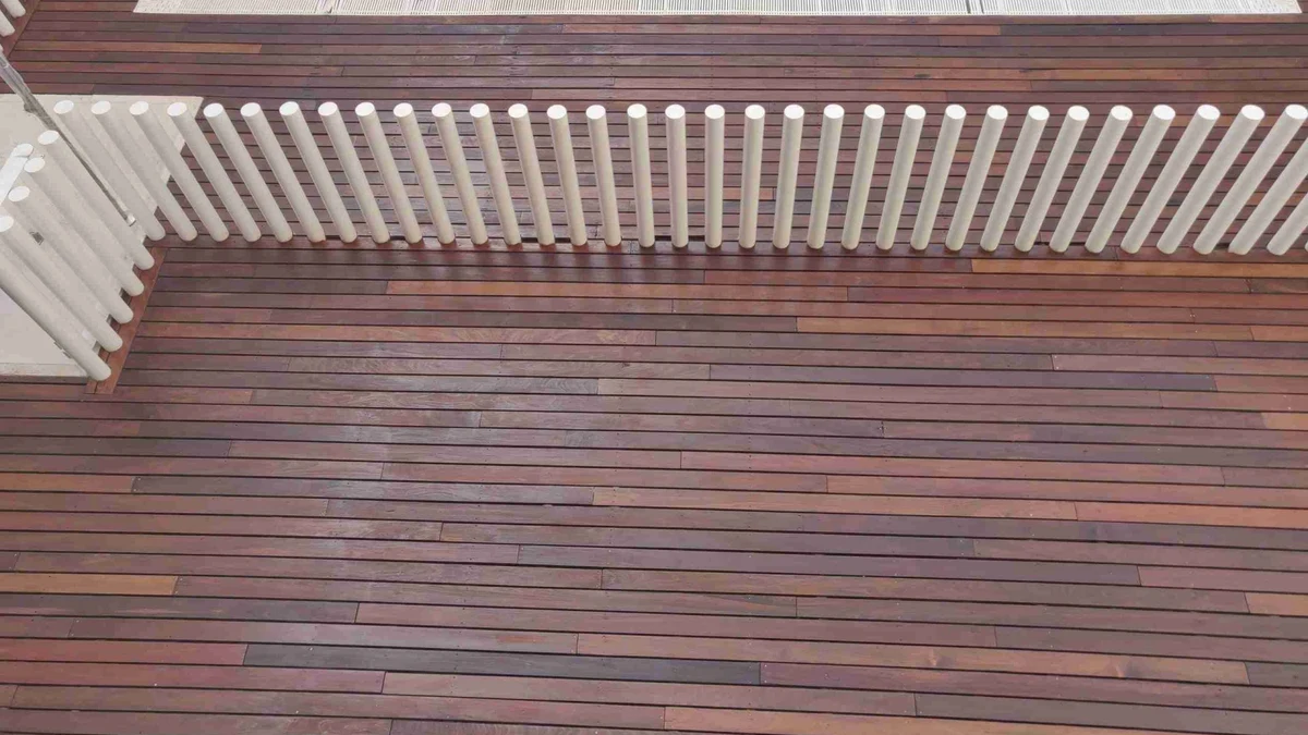 Tarima exterior de Ipé macizo en perímetro de piscina restaurada con tono castaño oliva y saturador anti-UV