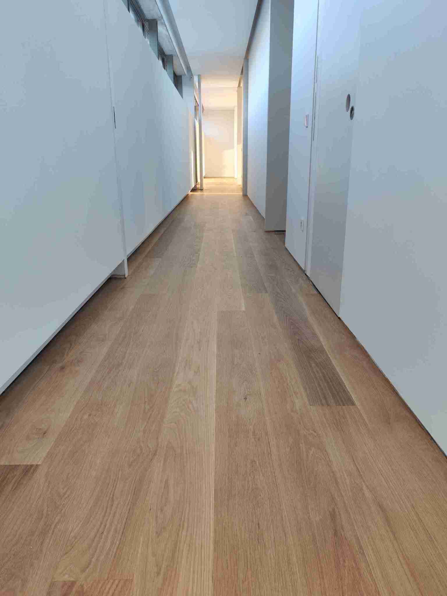 Suelo continuo de roble macizo restaurado y barnizado con Deva Plus Transit Natur en vivienda de Pozuelo.