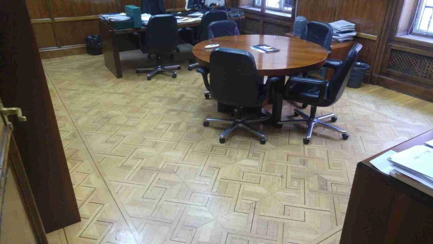 Despacho con mesa y sillas sobre parquet de marqueteria antes de restaurar