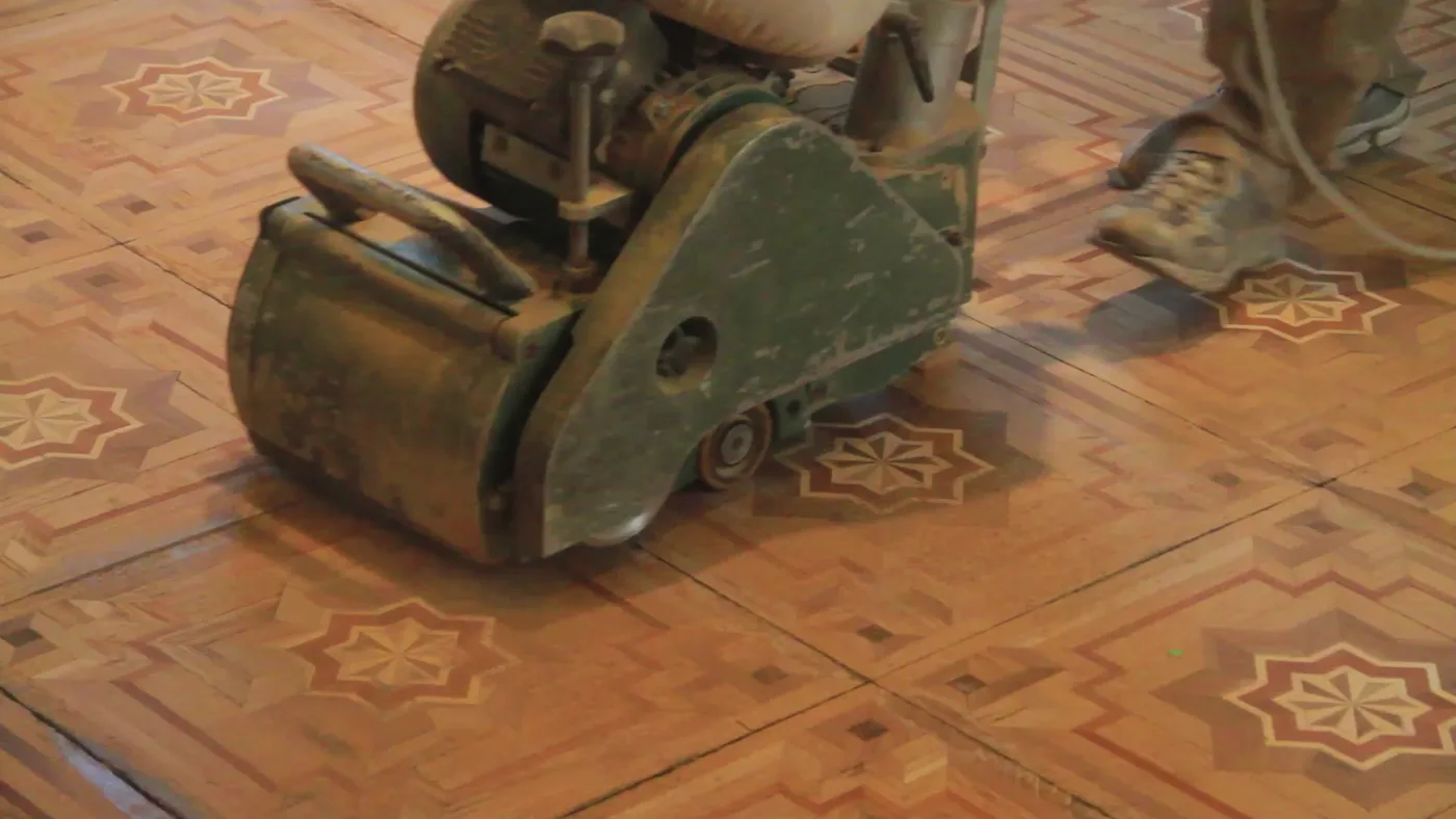 Detalle de máquina de acuchillar parquet trabajando sobre suelo de madera