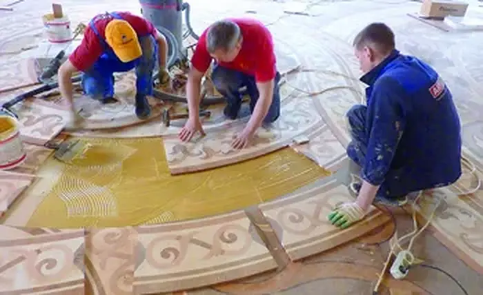 Operarios colocando piezas de parqué artístico del Hermitage durante la restauración