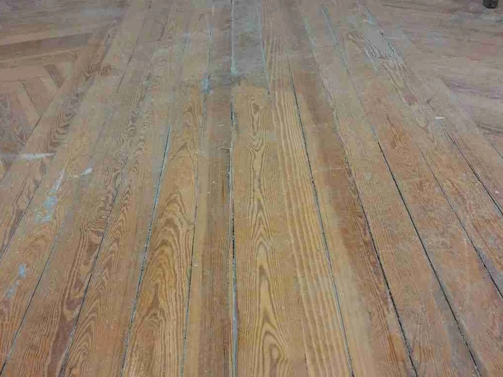 Tarima de pino melis con la superficie gastada y las juntas oscuras entre las tablas, antes de restaurar