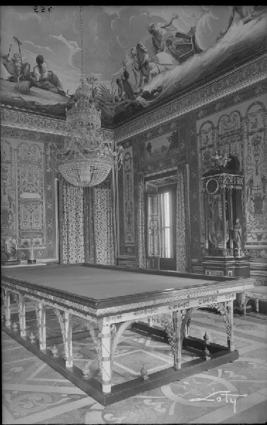 Fotografía antigua en blanco y negro de la sala de billar con la mesa y el pavimento original con dibujos