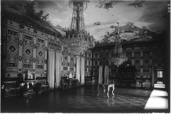 Fotografía antigua en blanco y negro de un salón con lámparas de cristal, sedas en las paredes y suelo de madera
