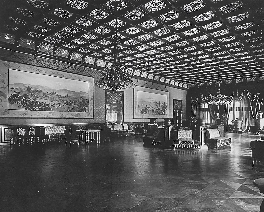 Foto de época de un salón con techo de casetones, lámparas de araña, sillones y un suelo brillante