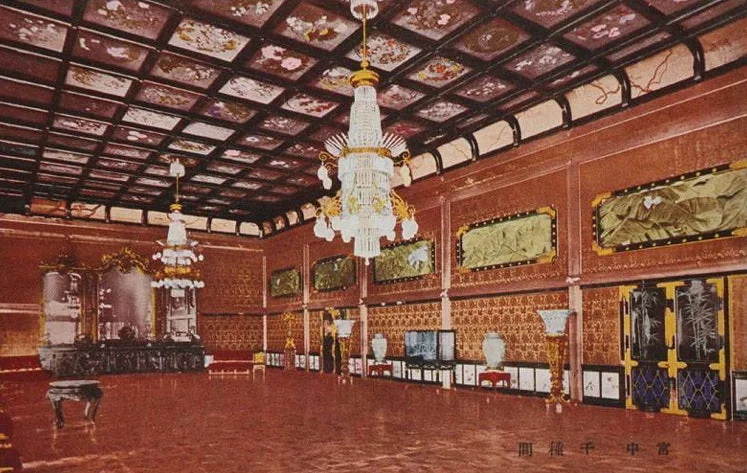 Postal coloreada de un salón con lámparas de araña y techo de casetones, sobre un suelo rojizo y brillante