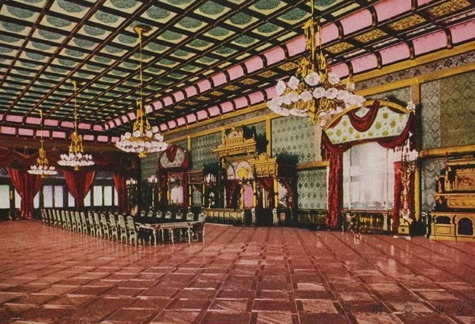 Postal coloreada de un gran salón con techo de casetones, lámparas y un suelo de cuadros grandes enmarcados por bandas oscuras