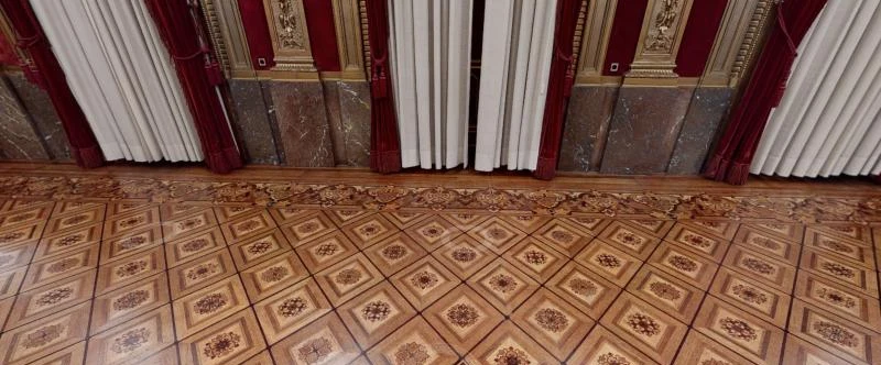 Rombos de taracea con marco de madera clara y rosetones más oscuros, junto a la greca y el zócalo de mármol