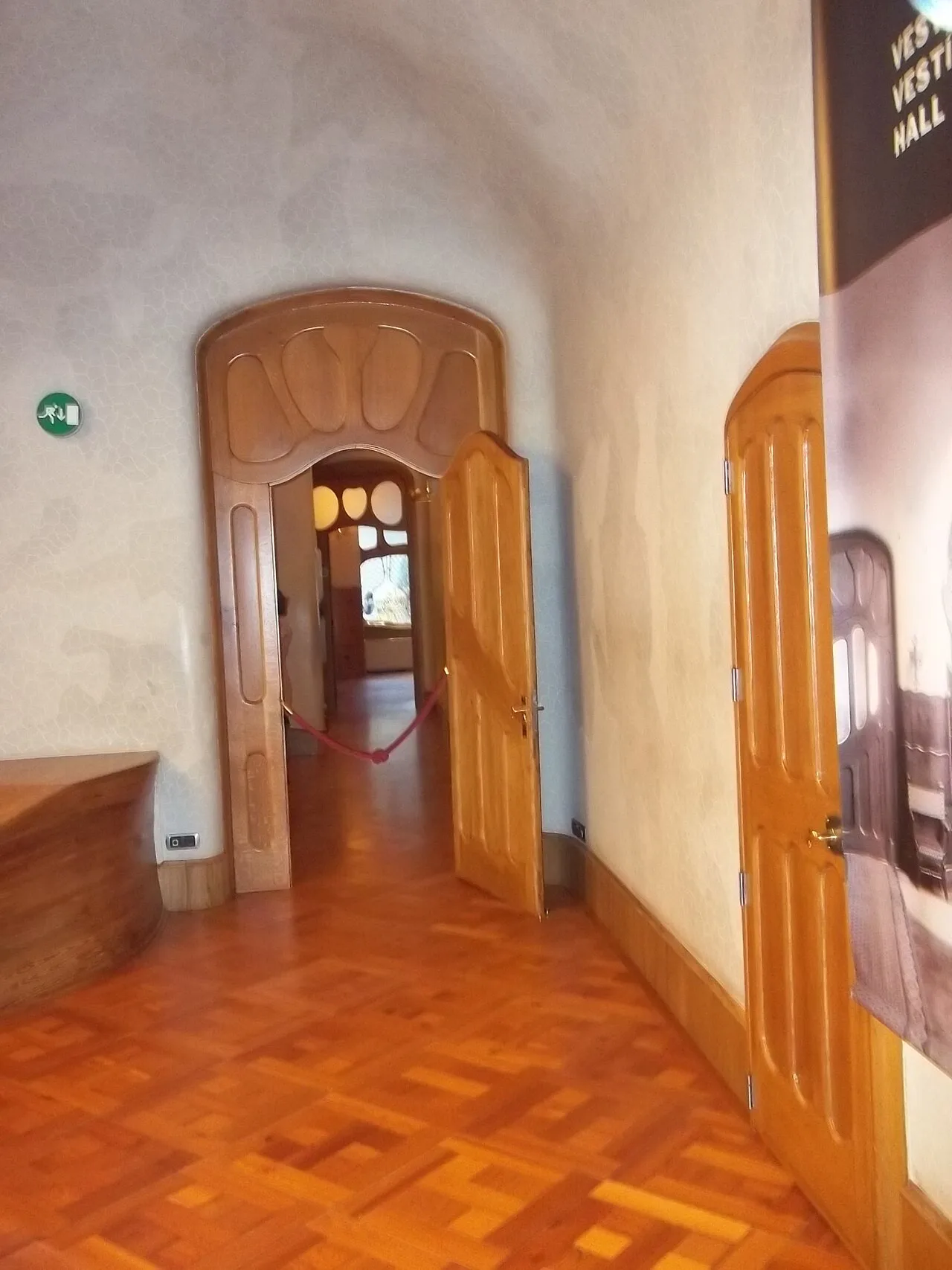 Vestíbulo de la planta noble de la Casa Batlló con suelo de losetas de tablillas en diagonal, puertas de madera y un zócalo de madera al pie del muro