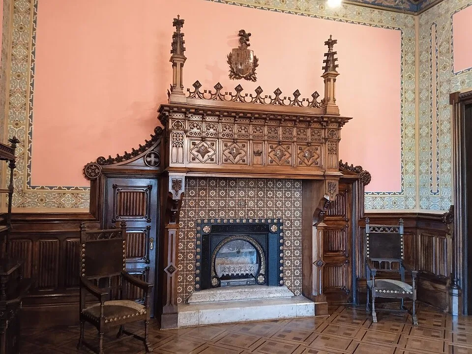 Sala con chimenea de madera tallada, azulejos y suelo de parquet en damero