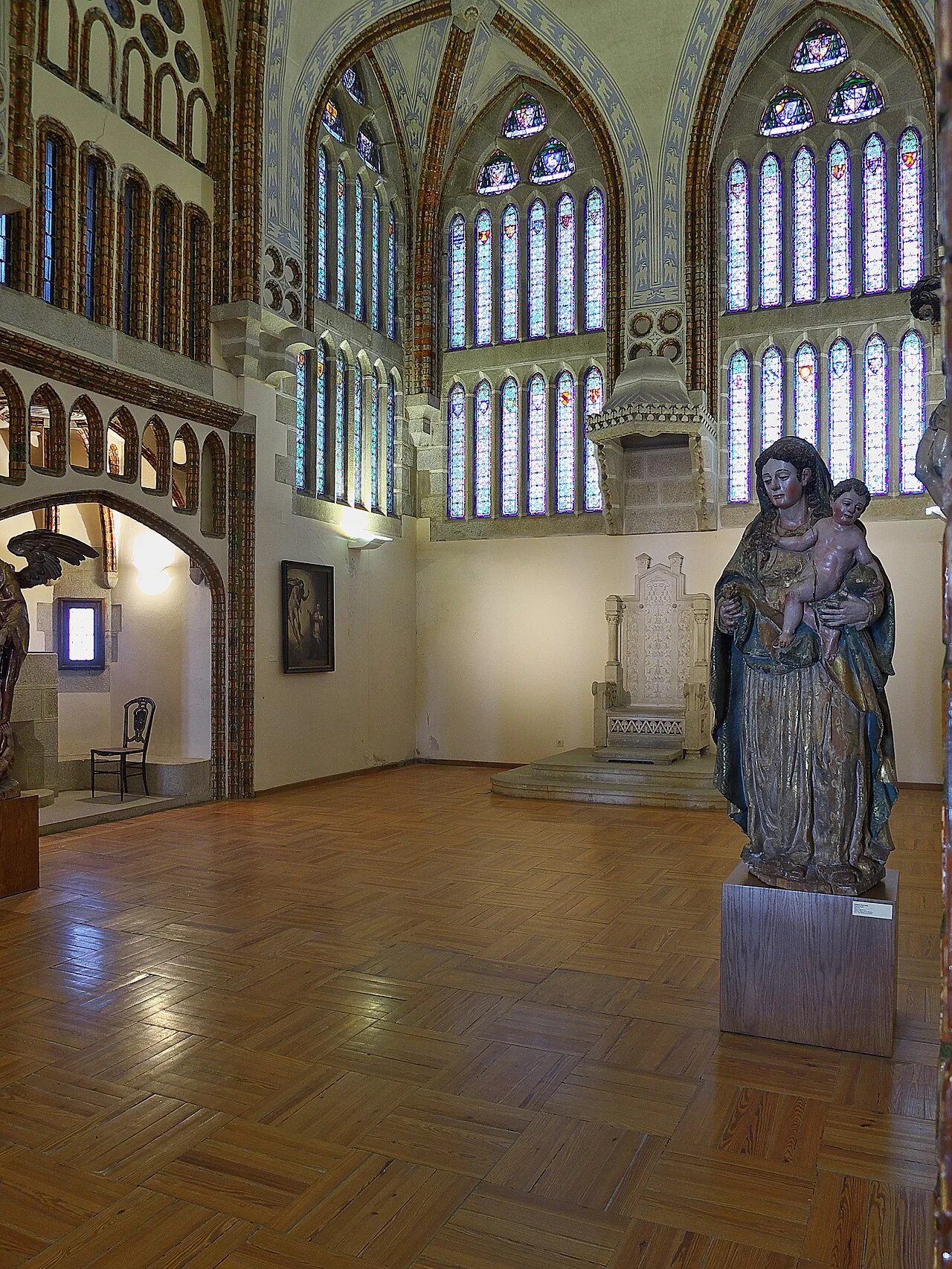 Salón del Trono del Palacio Episcopal de Astorga con parquet de cuadros de tablillas, el trono de piedra sobre su grada y una talla de la Virgen