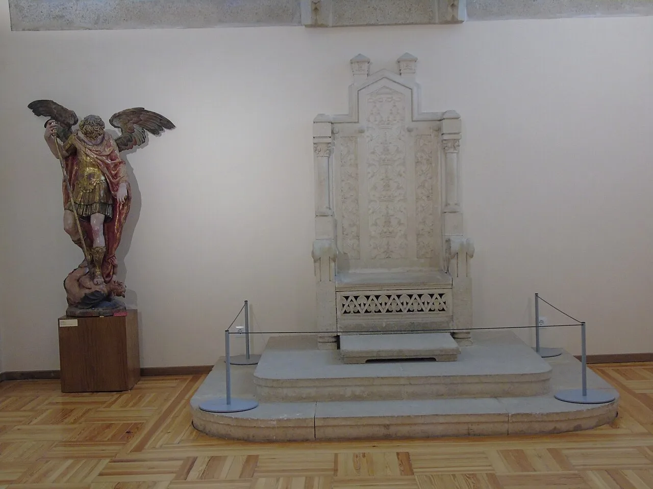 Trono de piedra del Palacio Episcopal de Astorga sobre su grada, con el parquet de cuadros de tablillas alrededor