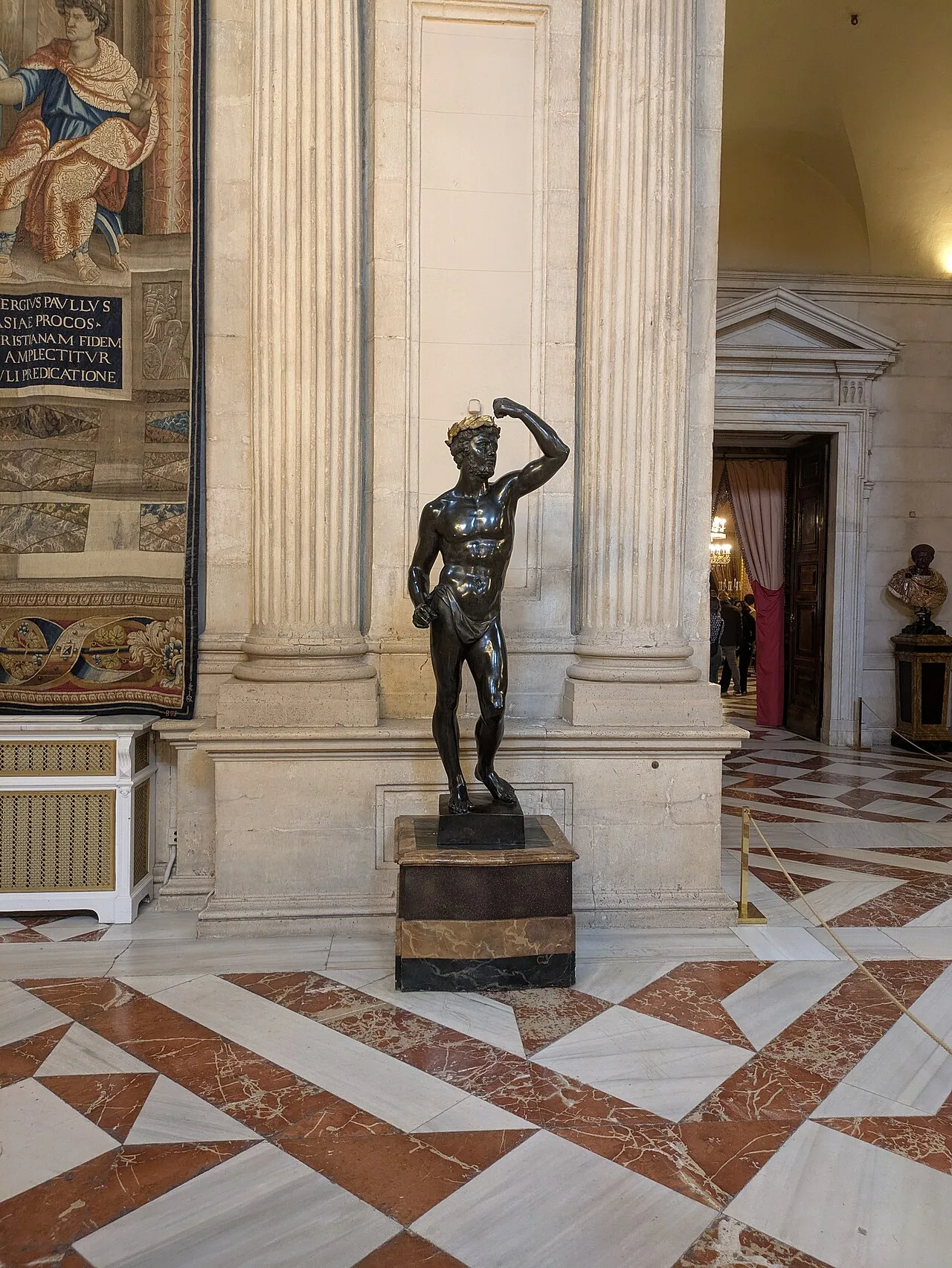 Suelo de piedra en bandas blancas y rojas del Salón de Columnas, con una estatua de bronce y una columna