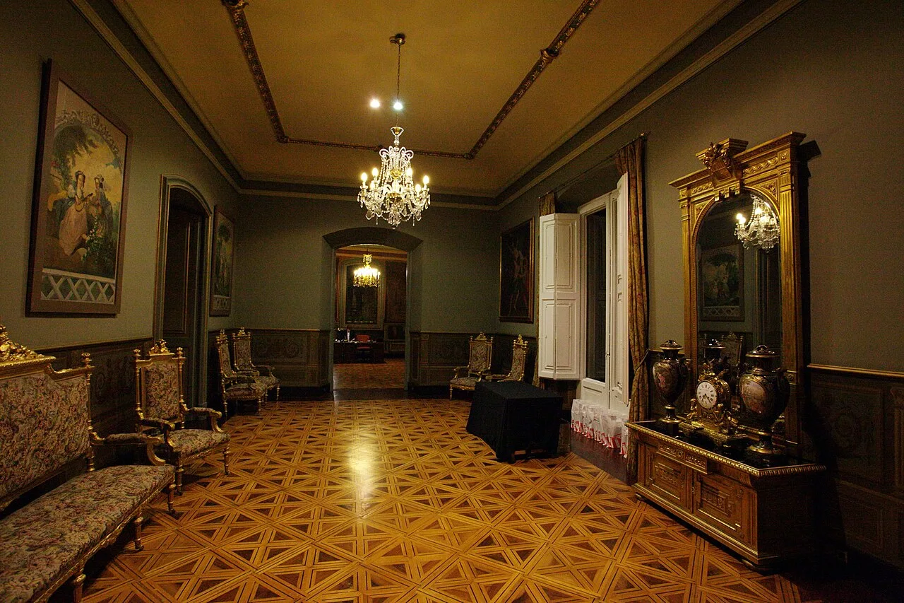 Antesala del Palau Moja vista desde el extremo opuesto, con consola dorada, sofá tapizado y parquet geométrico brillante