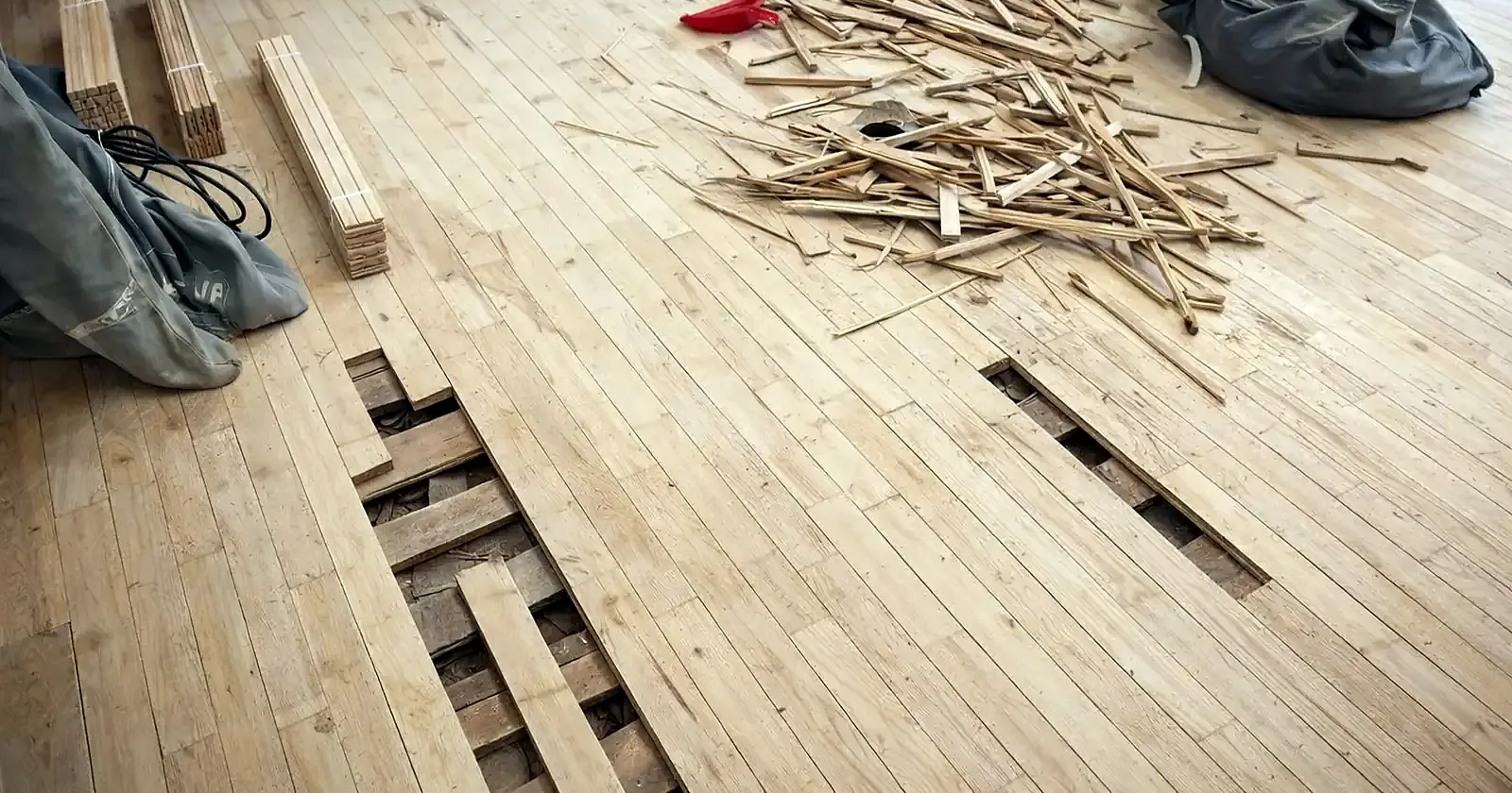 Tarima de castaño lijada con dos franjas de tablas levantadas que dejan ver la madera de debajo, junto a un montón de virutas